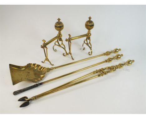 A pair of late Victorian brass fire dogs and associated fire tools The dogs with lobed ball finials and raised on scroll feet