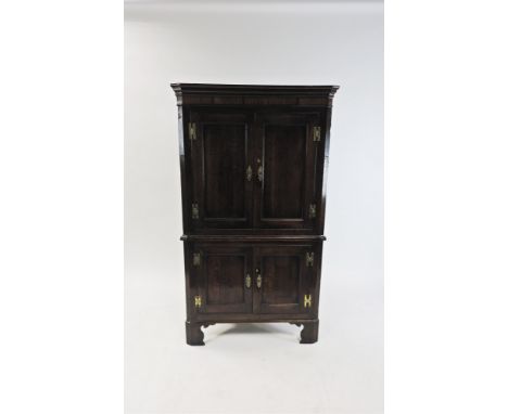 A George III oak and mahogany crossbanded free standing straight front corner cupboard, the moulded cornice above two indente