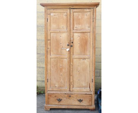 A 19th century pine tall hall cupboard fitted three shelves enclosed by a pair of panel doors above a long drawer, &amp; on a