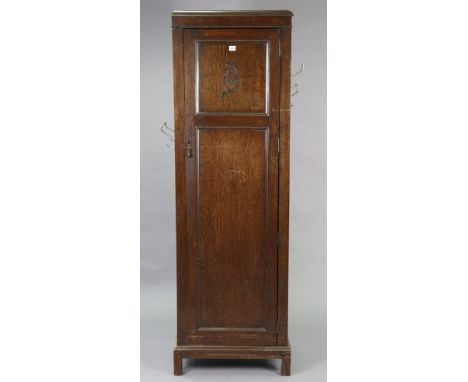 A mid-20th century oak tall hall cupboard enclosed by a panel door, &amp; on a shaped plinth base, 23¼” wide x 73¼” x 15½” de