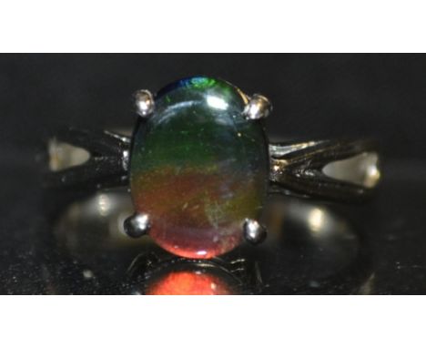 A simulated black opal doublet ring, oval simulated black opal panel, flashing green, red, orange and purple colour play, tap