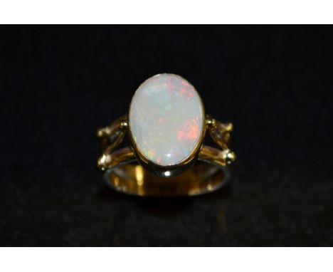 An oval opal doublet dress ring, flashing red, green, blue and purple colour play, 9ct gold contemporary double band shank,si