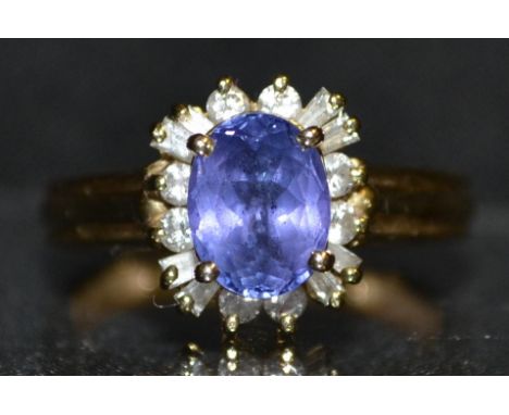 A tanzanite and diamond cluster ring, central raised quarter claw set tanzanite, above a band of sixteen round and irregular 