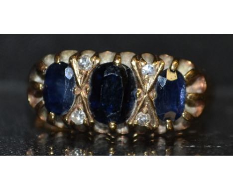 A sapphire and diamond ring, three graduated oval deep blue sapphires each divided by a pair of diamond accents, 9ct rose gol