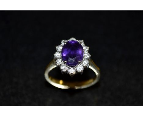 A diamond and amethyst cluster ring, central oval deep purple amethyst surrounded by a band of twelve round cut diamonds, 18c