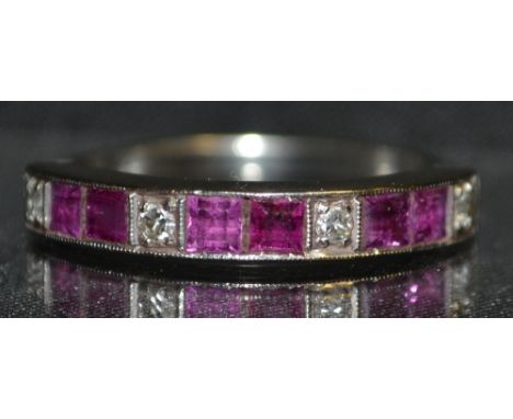 An Art Deco diamond and ruby half eternity ring, set with three pairs of pale pinky red square cut ruby's, each pair separate