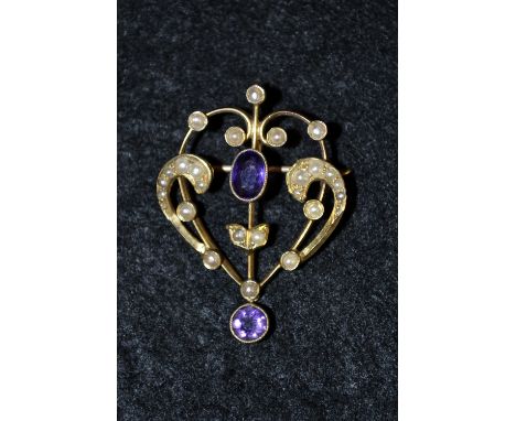 An Art Nouveau 9ct gold amethyst and seed pearl sweetheart brooch. open scrolling heart central set with an oval amethyst, ab