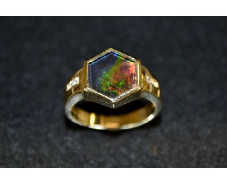 A Gentleman's synthetic black opal and diamond ring, hexagonal iridescent panel, tapering two stone diamond channel set shoul