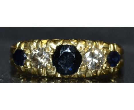 A sapphire and diamond five stone ring, central oval deep blue sapphire flanked to either side by a round brilliant cut diamo