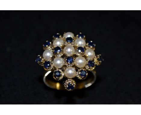 A sapphire and cultured pearl cluster ring, arching square lattice of alternating cultured pearls and round cut sapphires, op