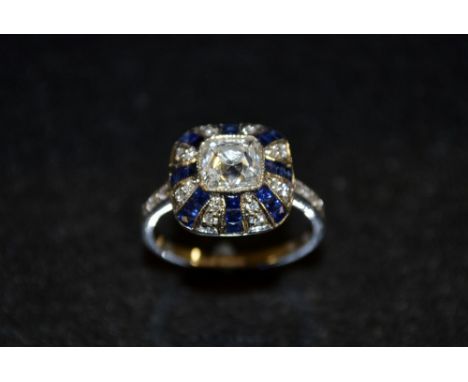 An Art Deco sapphire and diamond ring, central cushion cut diamond surrounded by alternating diamond and sapphire stripes, to