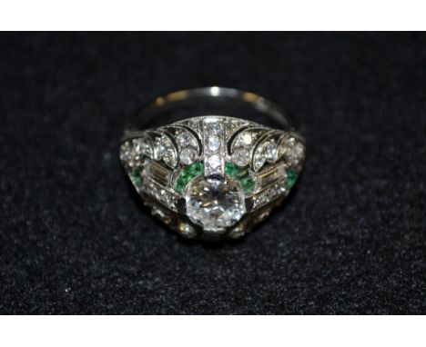 An Art Deco diamond and emerald cluster ring, central round brilliant cut diamond, approx 1ct, surrounded by a pave diamond a