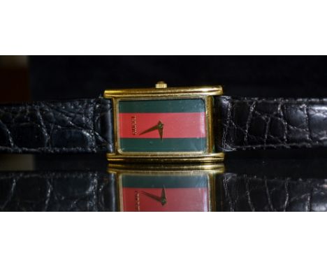 Gucci - a stripe faced dress watch, arching rectangular gold plated case, triple striped dial, arrow hand, quartz movement, b