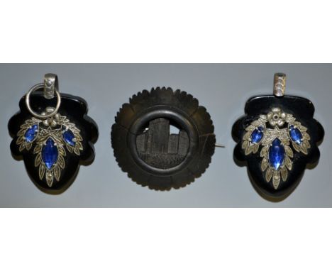 A carved bog oak shield brooch, central open panel carved with a castle, twelve section conical surround, unmarked, 46mm diam