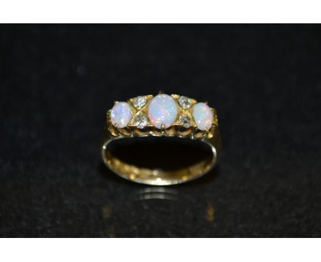 An opal and diamond seven stone ring, three oval opal doublets, flashing orange, green and blue colour play, each divided by 