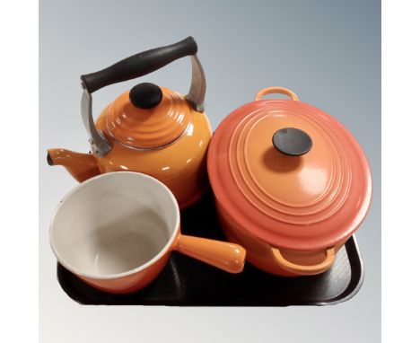 A Le Creuset cast iron lidded casserole pan together with a Le Creuset kettle and sauce basin.
