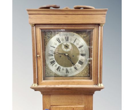 A Scandinavian oak longcase clock with brass and silvered dial, pendulum and weights.