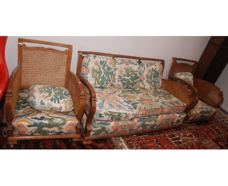 A walnut bergere three seat art deco sofa and a pair of matching armchairs.