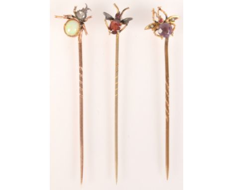 Two gold fly pins one set with a diamond and an opal together with a third fly pin. 