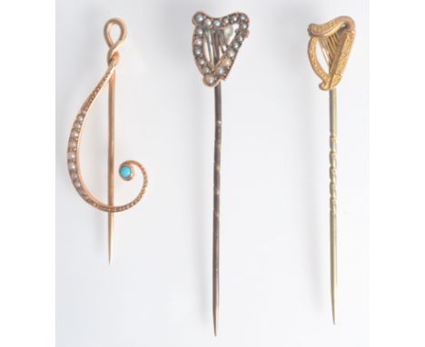 A 15ct. gold treble clef pin set with turquoise and pearls, a 9ct. gold harp mounted pin and a seed set gold harp pin.