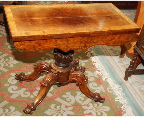 A Victorian walnut card table with cross banded fold top on carved pedestal and ornate quadruple base.