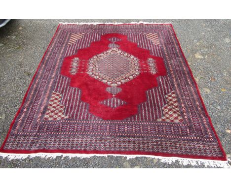A Pakistan carpet, the red field with a central polychrome pole medallion, within multiple borders, 299 x 249cm.  26cm of sid