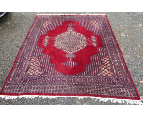 A Pakistan carpet, the red field with a central polychrome pole medallion, within multiple borders, 299 x 249cm.  26cm of sid