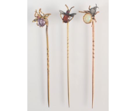 An Edwardian pin with garnet and ruby fly finial together with two other insect gold mounted pins.