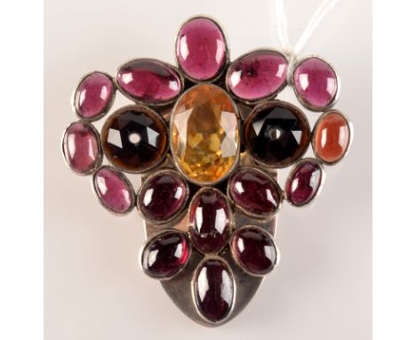 An Arts and Crafts silver clip set with cabouchon garnets, and a faceted citrine.  Condition report: There is a strange tarni