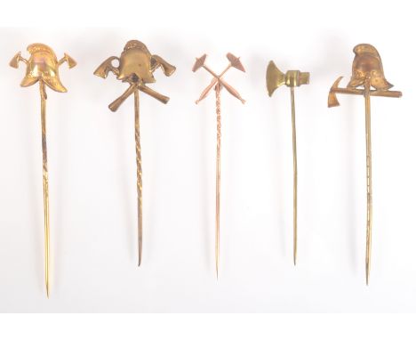 A gold fireman's helmet pin and two other gilt fireman's helmet pin, a crossed hammers gold pin and an axe pin.