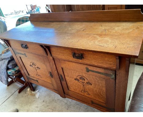 Early C20th Art Nouveau oak sideboard, low raised back and two frieze drawers over two panel doors carved with stylised folia