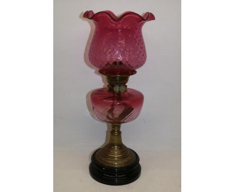 Victorian oil lamp, with black ceramic base, embossed brass column, cranberry glass reservoir and shade, lacking chimney, H50