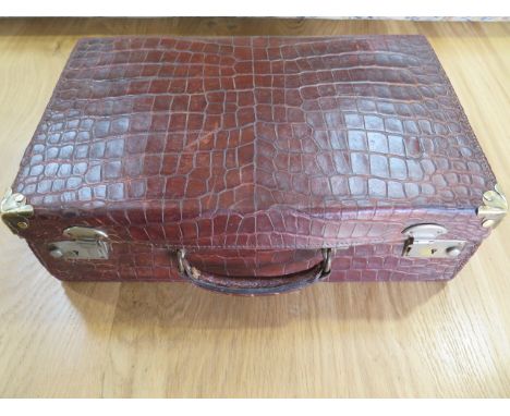A vintage crocodile travel suitcase, 43cm x 28cm x 13cm , with wear and repair consistent with use and age but a good colour 