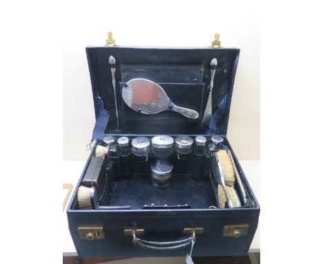 A Mappin and Webb blue leather fitted travel case with 8 silver top bottles, 4 silver back brushes and mirror, comb cover, ma