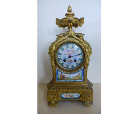 An ormulu and porcelain striking mantle clock surmounted by a lidded urn - 36cm tall, runs and strikes, porcelain plaques gen