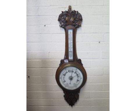 A carved oak aneroid barometer with thermometer - 90cm long 