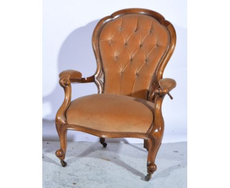 A ladies mahogany framed button back armchair, with scrolling arms and cabriole legs with castors, upholstered in a beige vel