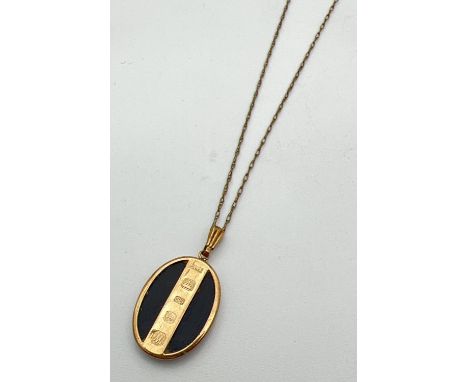 An oval shaped 9ct gold and black onyx pendant with hallmarks to front. On a 19" fine rope chain with spring ring clasp. Tota