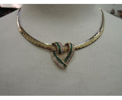 A yellow metal emerald and diamond heart shaped open slide pendant stamped 14K having 29 channel set emeralds and 43 channel 