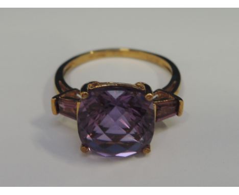 A ladies dress ring having a large amethyst style stone flanked by two pink tourmalines in a raised setting on a 9ct gold loo