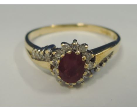 A ladies dress ring having a ruby and diamond cluster with further diamonds to shoulders on an 18ct gold loop