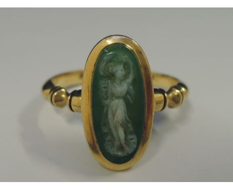 A ladies dress ring having a Jade style cameo depicting a Grecian lady in a collared mount to shaped shoulders on a yellow me