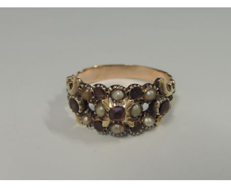 A Victorian ladies dress ring having seed pearl and ruby decoration with moulded shoulders on a yellow metal loop, no marks