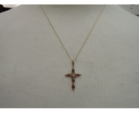 A 9ct gold cross pendant set with ruby chips and central diamond on a 9ct gold chain   