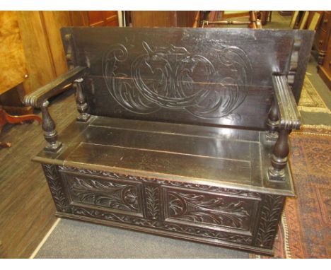 A mid 20th century dark oak monks bench in the Jacobean style having incised decoration