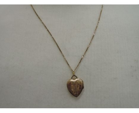 A yellow metal heart shaped locket stamped 10K on a yellow metal box chain stamped 10K