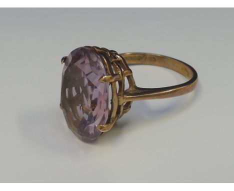 A ladies dress ring having a amethyst solitaire in a raised woven style mount on a 9ct gold loop