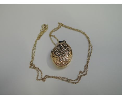 A 9ct gold oval locket having moulded decoration on a yellow metal chain stamped 375