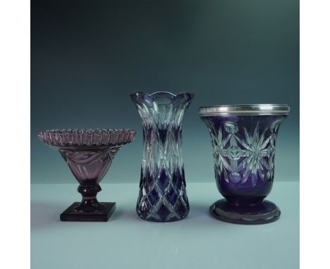 A striking collection of three amethyst and cut glass pieces, including two vases and a footed dish, each showcasing unique c