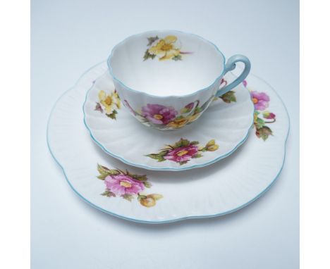 A three-piece Shelley bone china tea set in the Begonia pattern. The set includes a teacup, saucer, and tea plate, each adorn